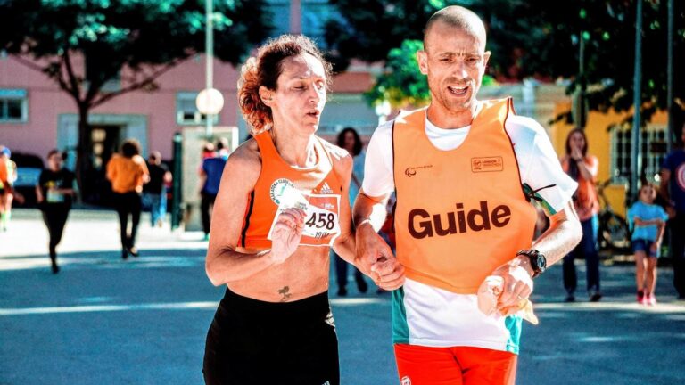 Guide runner running alongside an athlete during a race, helping maintain pace and endurance to avoid bonking