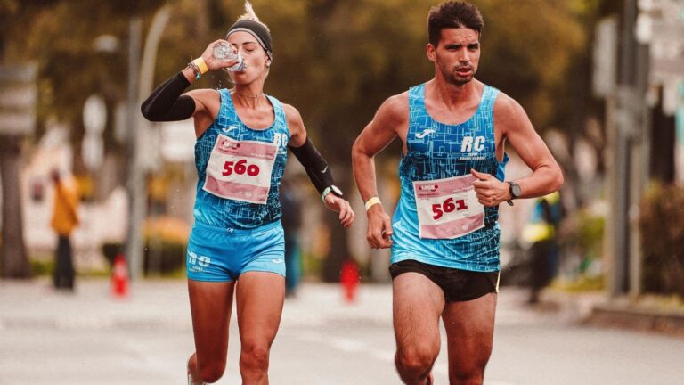 Two runners during long run, one drinking electrolytes to maintain hydration and energy levels