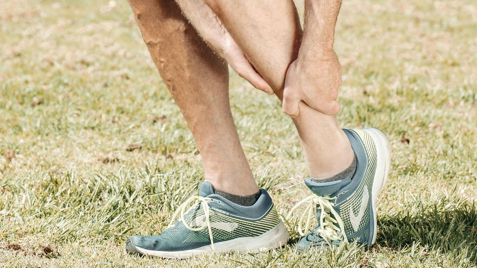 Runner stopping mid-run holding shin in pain, showing signs of common running injury