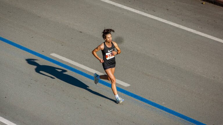 A marathon runner maintains a steady pace on the course, showing focus and endurance during a long-distance race.