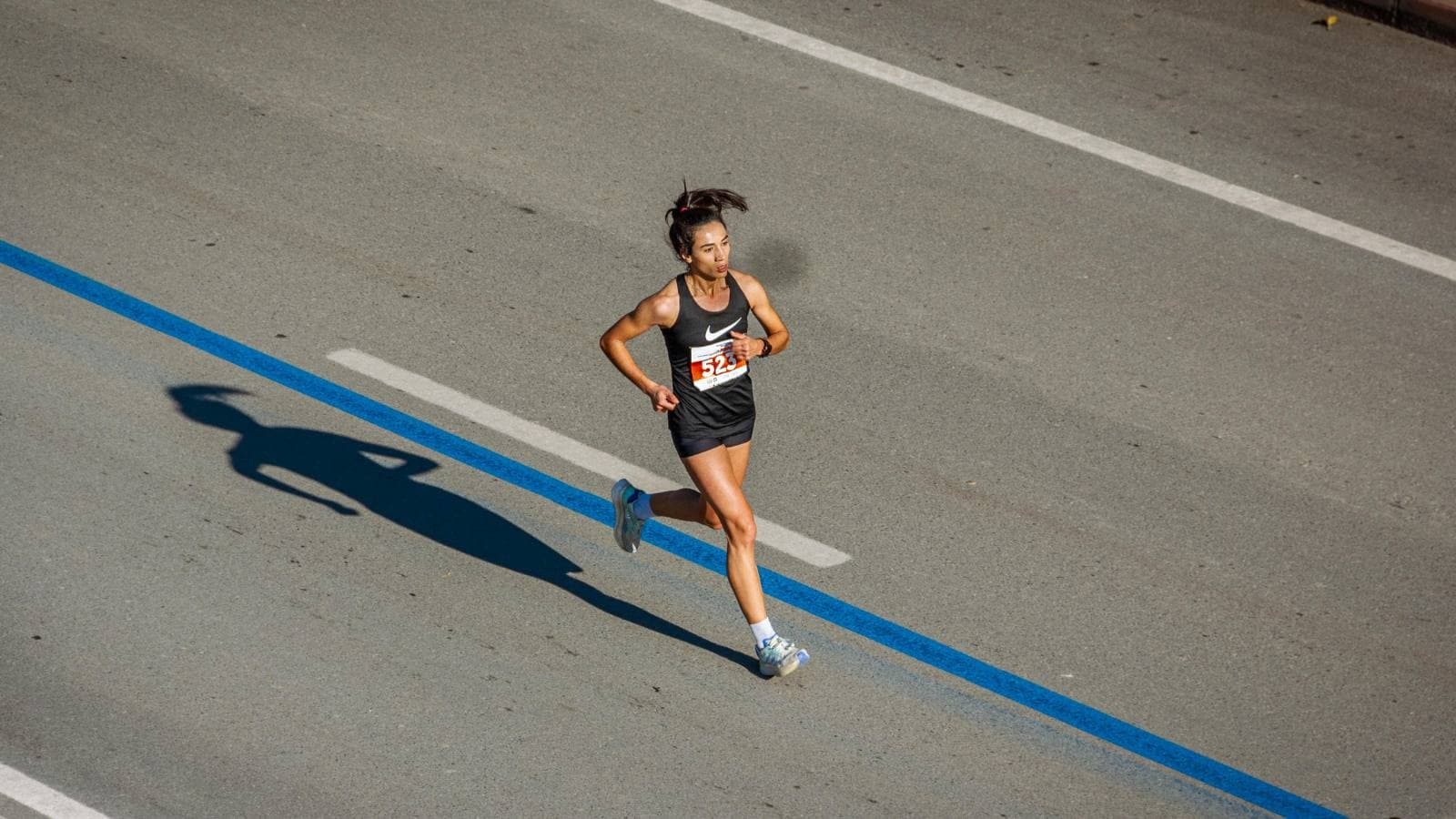A marathon runner maintains a steady pace on the course, showing focus and endurance during a long-distance race.