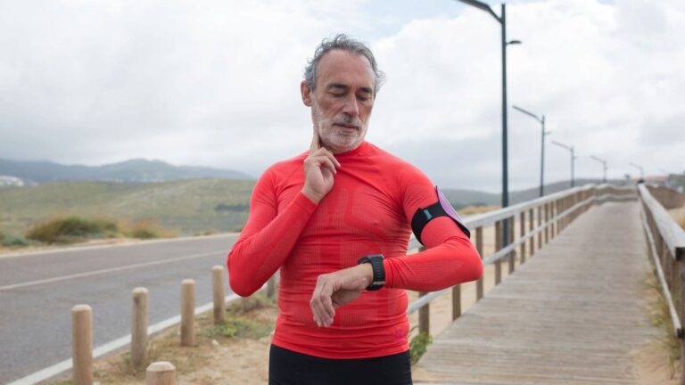 trail runner checking smartwatch data during trail run to monitor pace heart rate and elevation