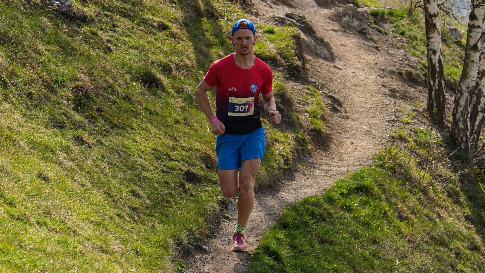 Trail runner descending a steep, rocky trail with controlled posture and quick foot placement to maintain stability.