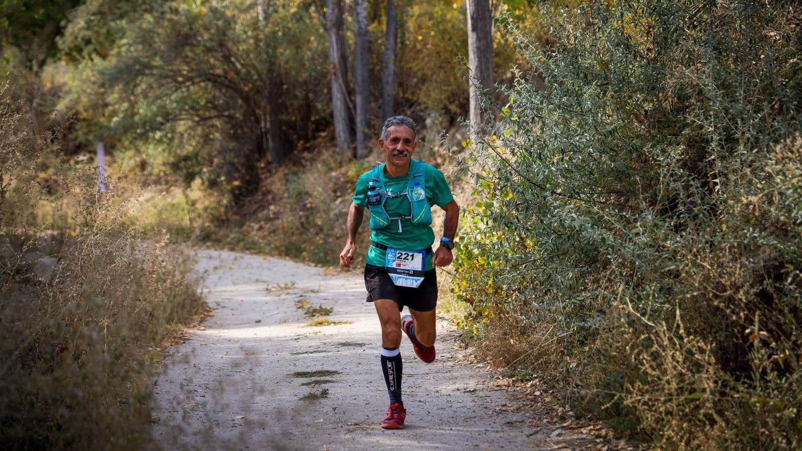 trail runner following consistent training plan on mountain trail while avoiding overtraining and injury