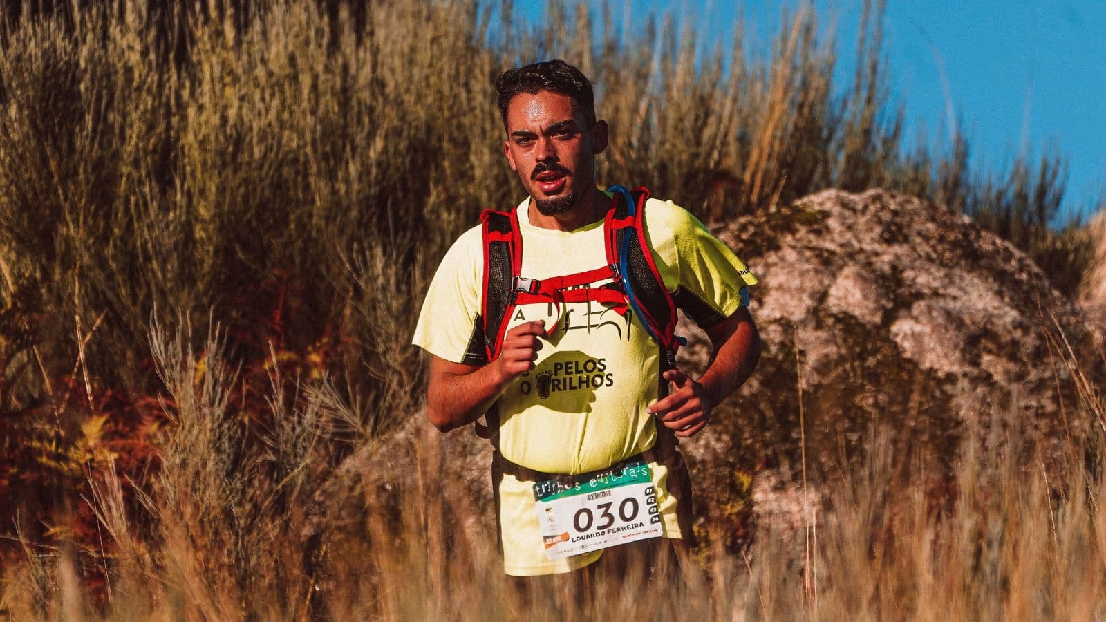 Trail runner maintaining a controlled pace while climbing a gradual uphill trail to manage breathing and conserve energy.