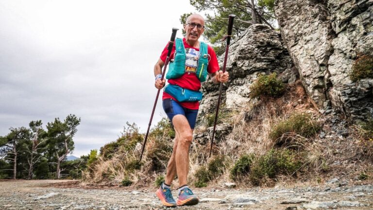 trail runner descending steep mountain trail with trekking poles for better control and reduced impact