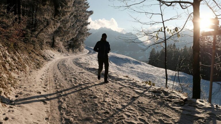 trail runner dressed in winter running gear on snowy trail to stay warm and avoid hypothermia