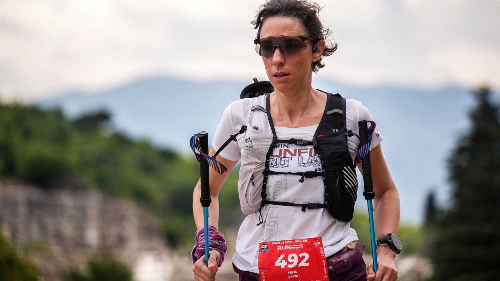 trail runner using trekking poles during steep uphill trail run to improve stability and climbing efficiency