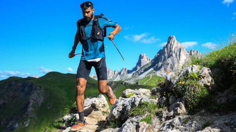 Trail runner power hiking a steep mountain climb during a long trail race to maintain a sustainable effort.