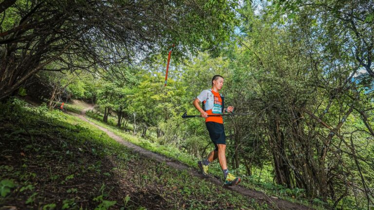 Trail runner using short, quick strides while descending a rocky mountain trail at a controlled pace.