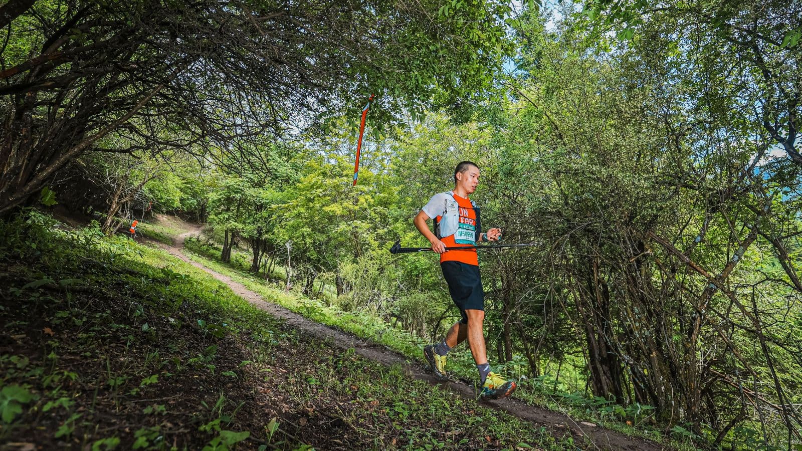 Trail runner using short, quick strides while descending a rocky mountain trail at a controlled pace.