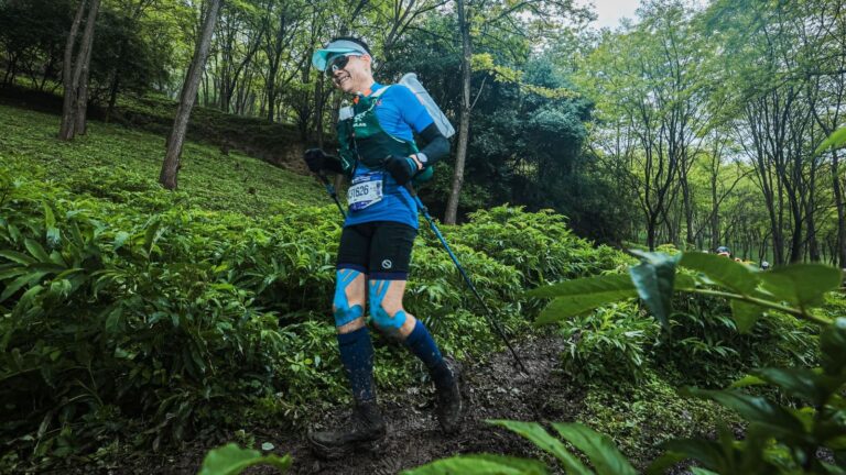 Trail runner moving at a controlled easy pace while climbing a long hill during an endurance training run.