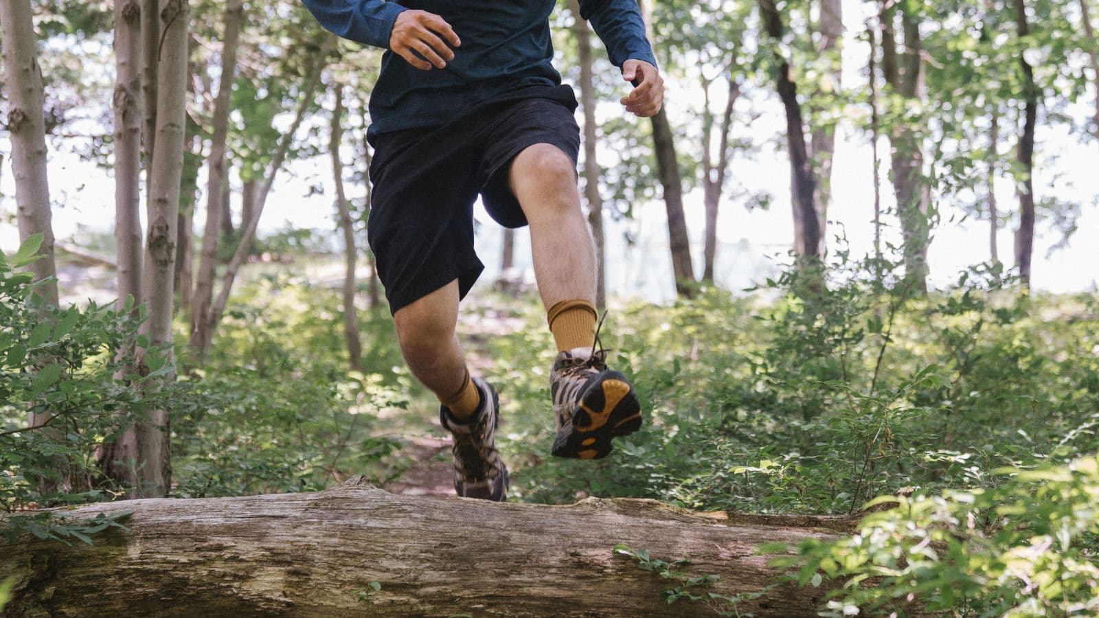 Solo trail runner checking a planned route on a phone and map before starting an off-road run.