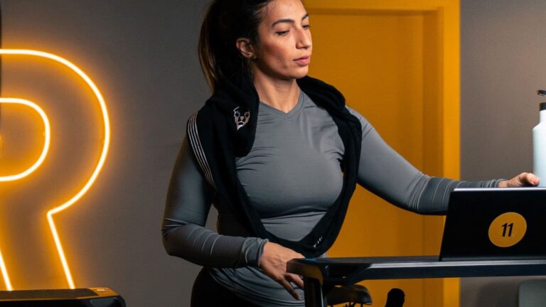 Runner adjusting an ergonomic sit-stand desk to change working position during a long office day between running workouts.