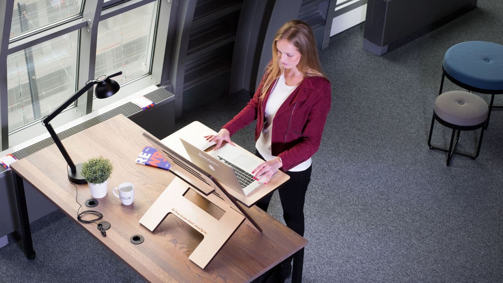 Recreational runner wearing comfortable athletic clothing while working at an adjustable standing desk in a home office.