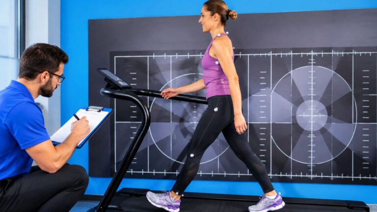 Running specialist reviewing slow-motion video footage of a runner's foot strike, stride, and lower-body movement.