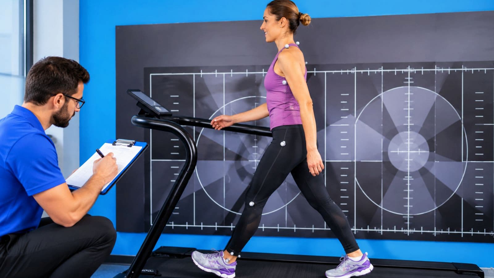 Running specialist reviewing slow-motion video footage of a runner's foot strike, stride, and lower-body movement.