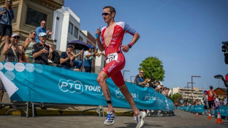 Distance runner accelerating past another competitor during a road race while maintaining controlled running form.