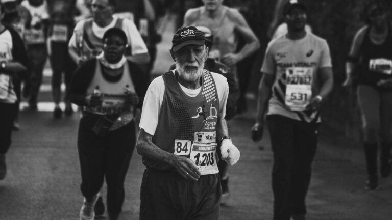 Older and younger ultrarunners running together during a long trail race while maintaining a controlled endurance pace.